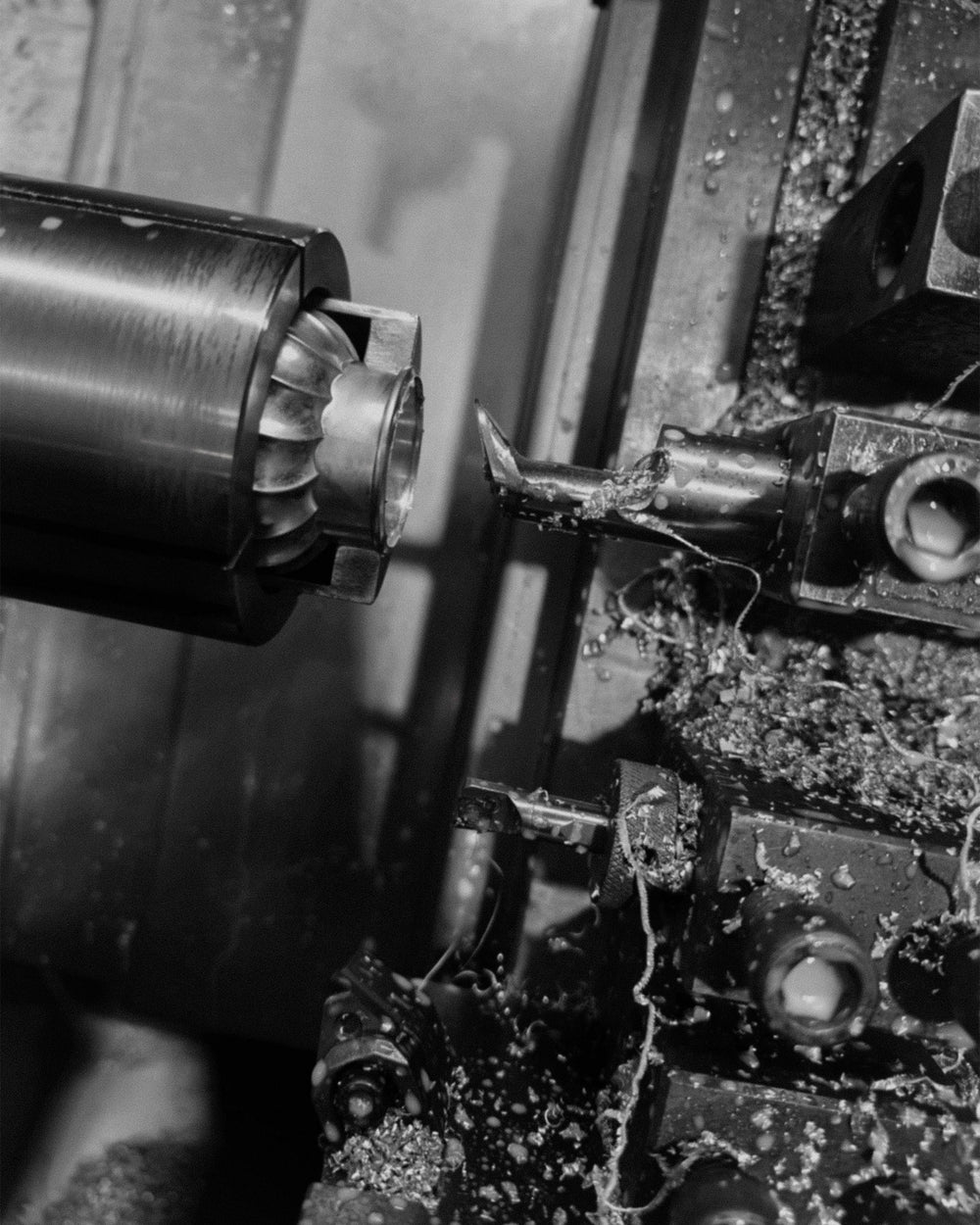 Close-up of a metal lathe in operation with a tool cutting into the zinc cap.